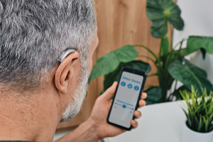 Hearing-impaired-man-adjusts-settings-for-his-BTE-hearing-aid-via-smartphone_shutterstock_620x330-300x200.png